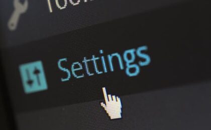 A close-up photo of a computer screen showing the settings button with a cursor hovering over it.